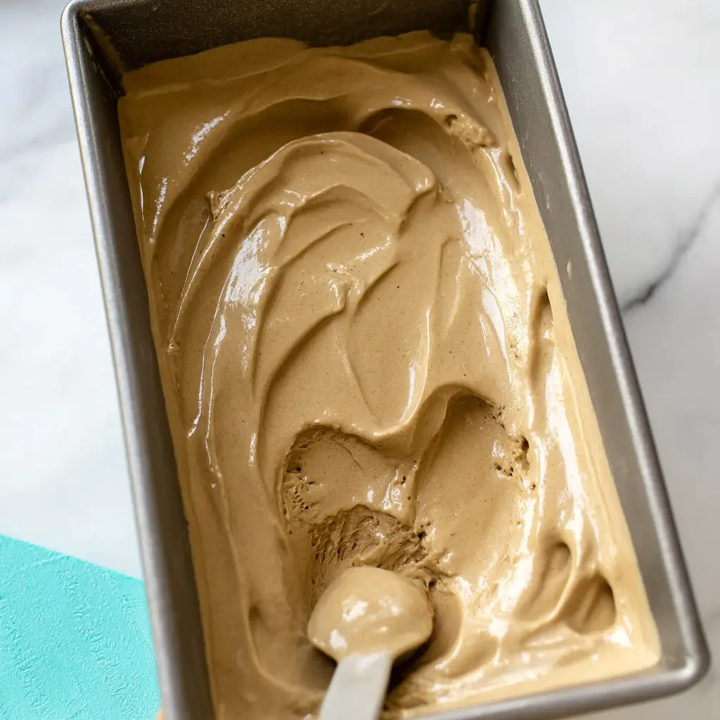 Pouring dairy free coffee ice cream mix into an ice cream maker